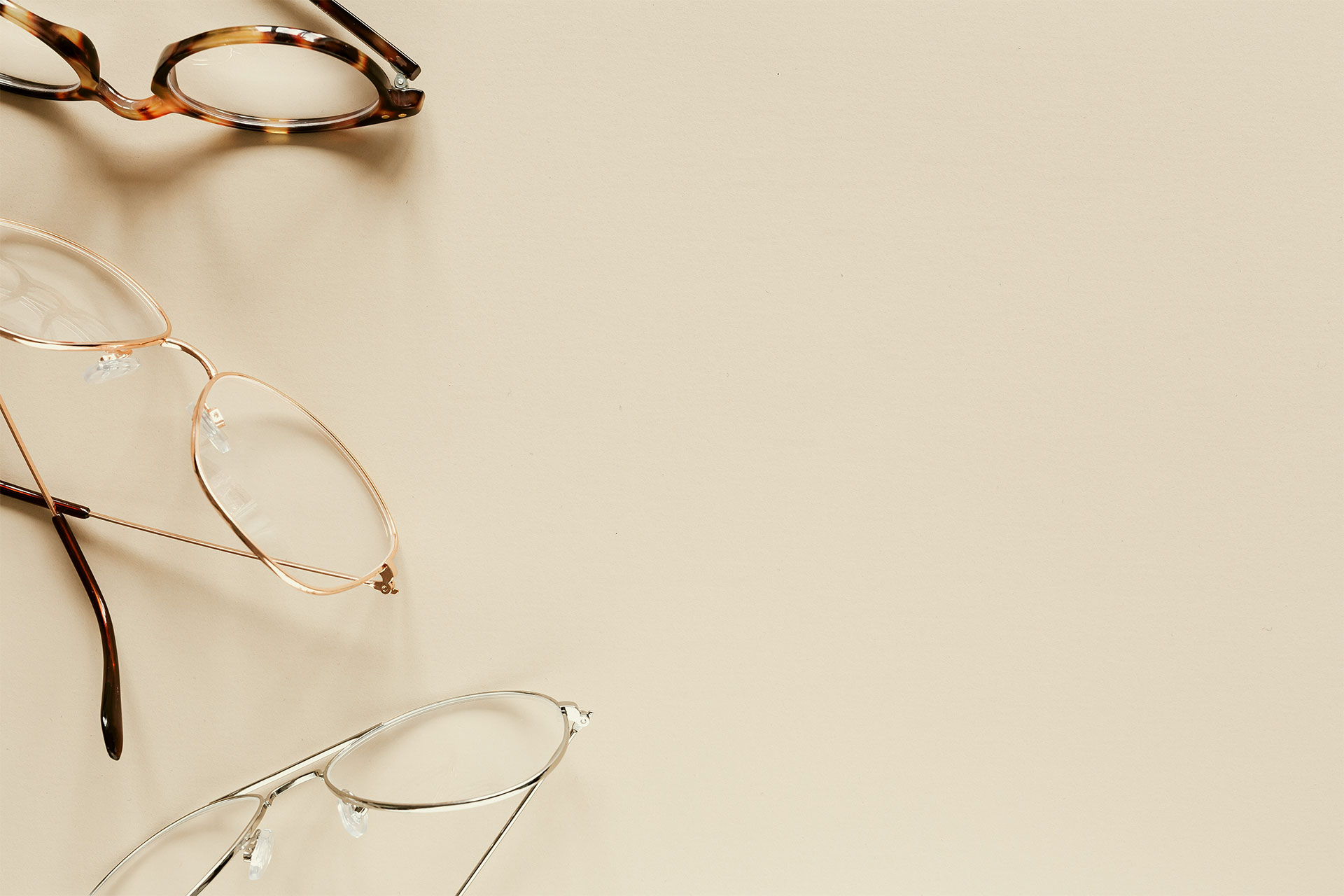 Vision Quest Optical Eyewear Header Three different styles of eyewear on a desk.